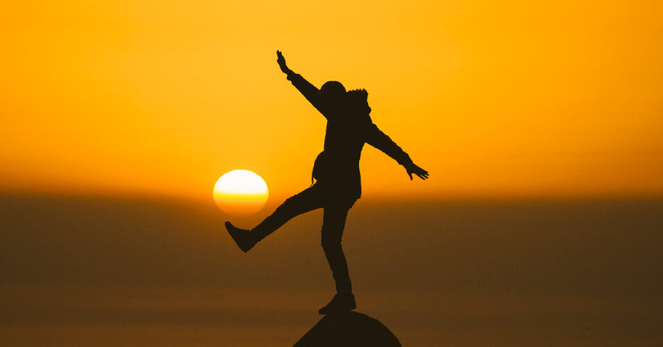 une personne sur une montagne avec le coucher du soleil en arrière plan